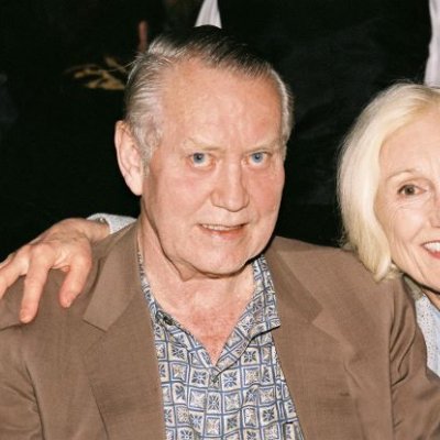 A man and woman sit side by side, smiling.